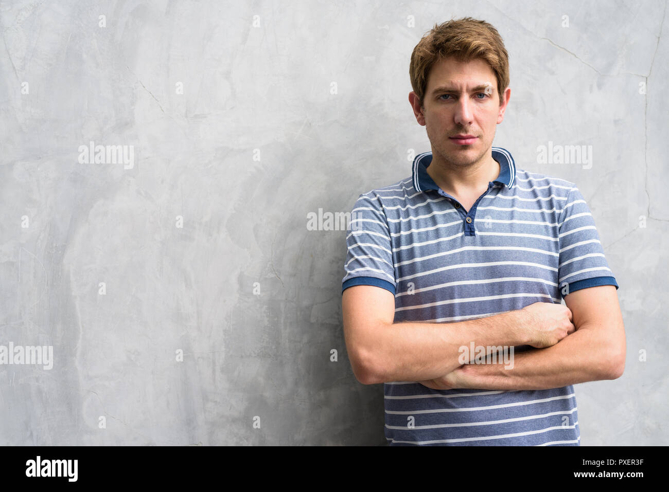 Portrait of handsome man with blond hair against concrete wall outdoors Stock Photo