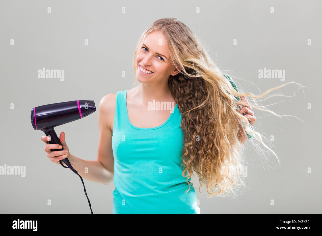 Young woman with long blonde hair using hair brush and