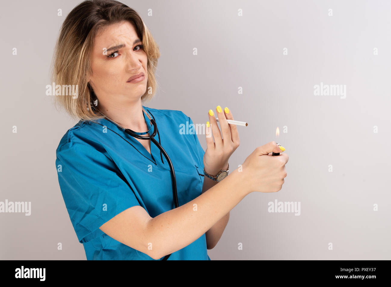 Female doctor with stethoscope, cigarette and lighter displaying