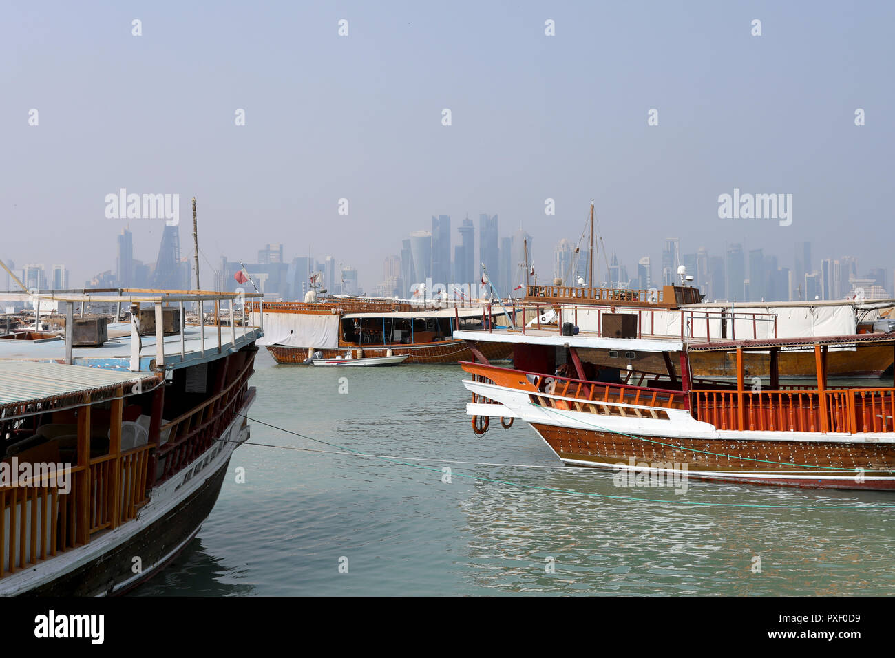 Doha / Qatar – October 10, 2018: Traditional dhows moored up along the corniche in the Qatari capital Doha, with the skyscrapers of the West Bay area  Stock Photo