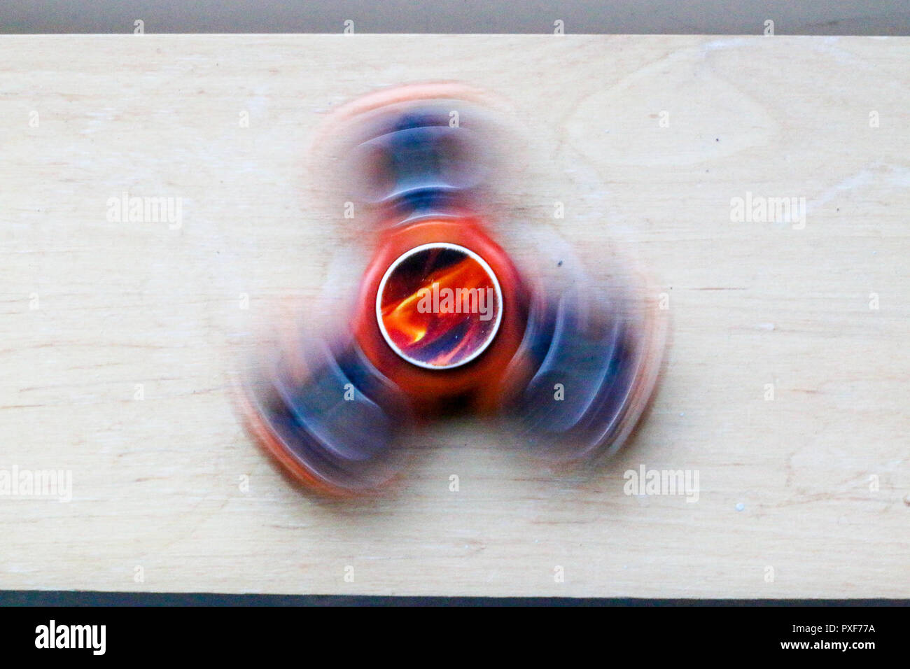 longer exposure photo of a fast moving fidget spinner with a orange/red paint Stock Photo
