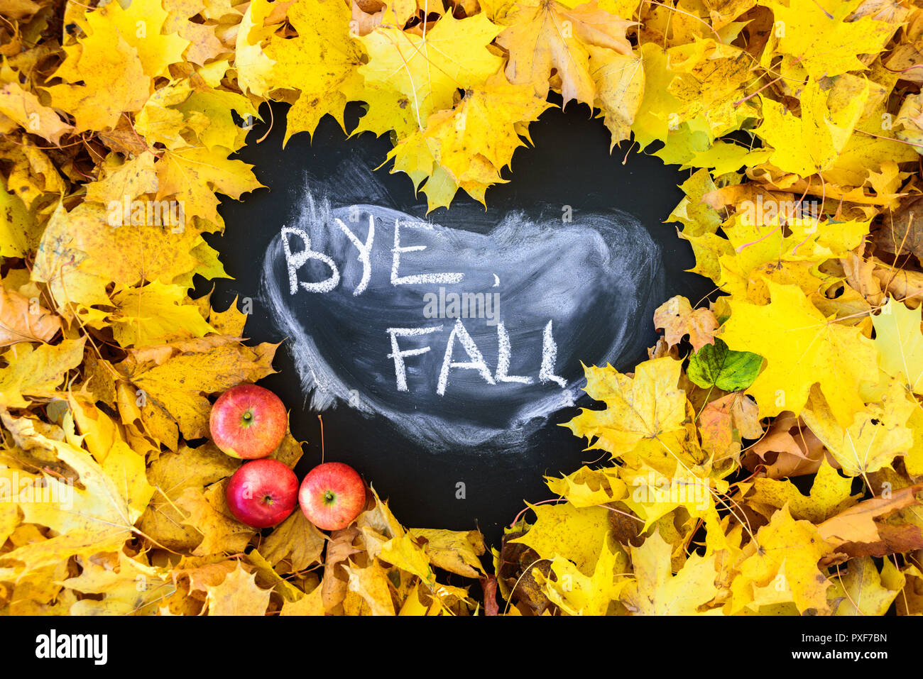 Blackboard with frame of leaves in heart shape. Word BYE FALL is written there Stock Photo