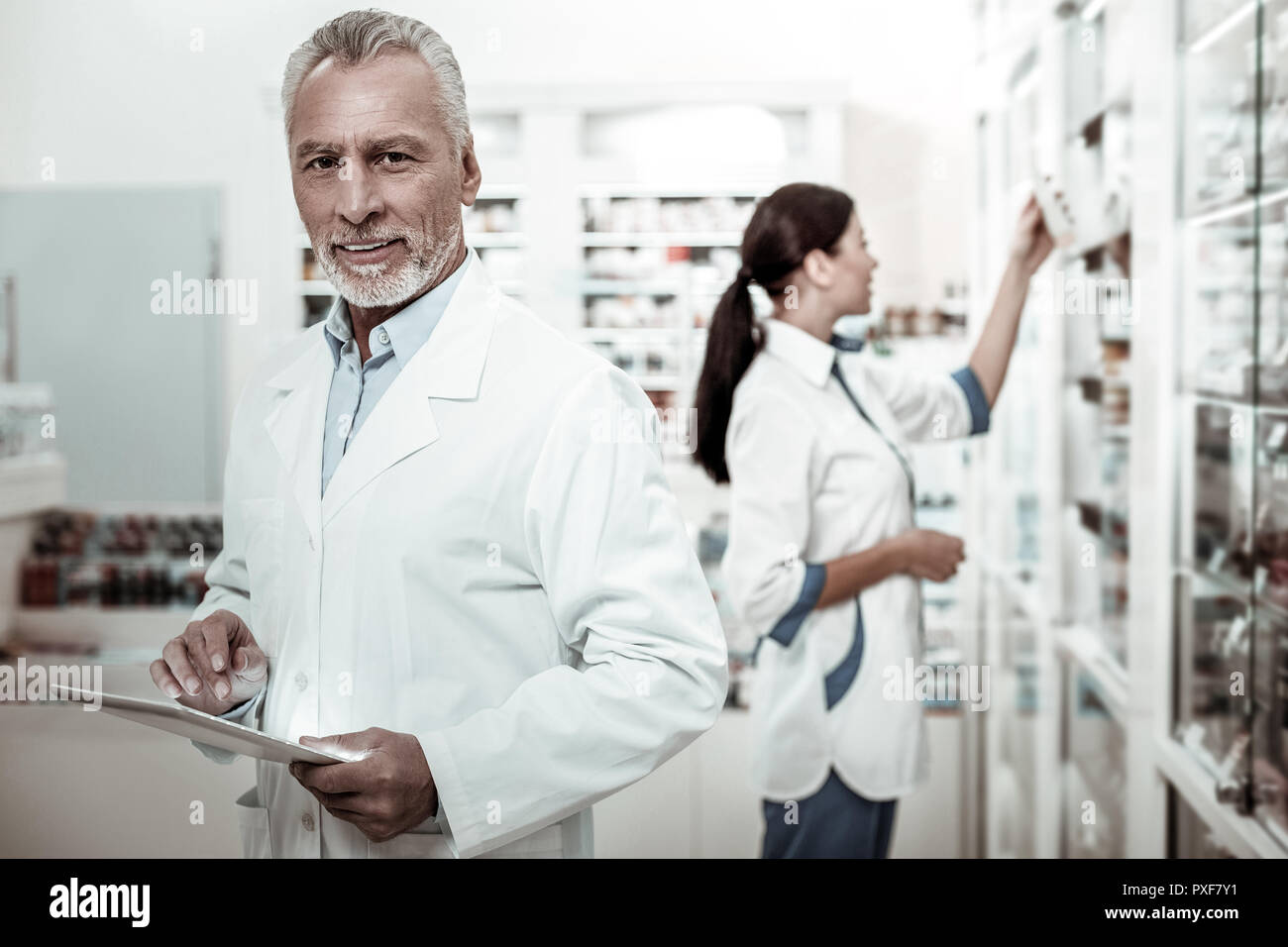 Bearded mature first-line pharmacist feeling joyful while working hard Stock Photo