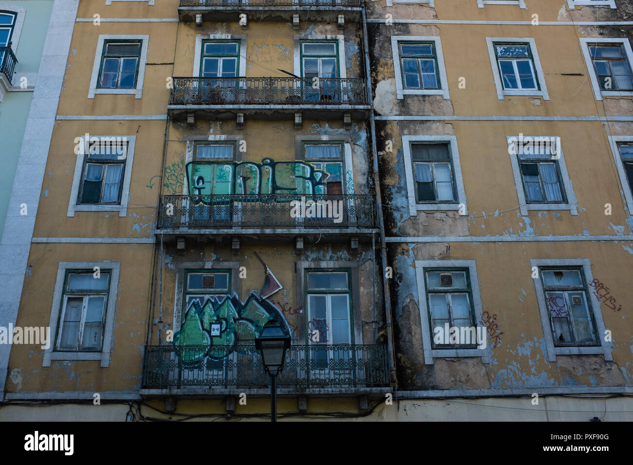 Exterior of a yellow building with graffiti, windows and balconies in Lisbon Portugal Stock Photo