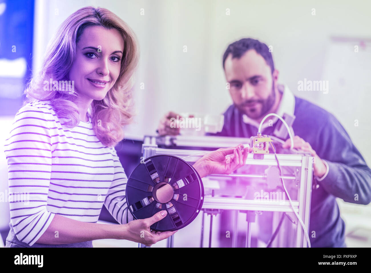 Two hard-working office workers feeling curious while standing near new device Stock Photo