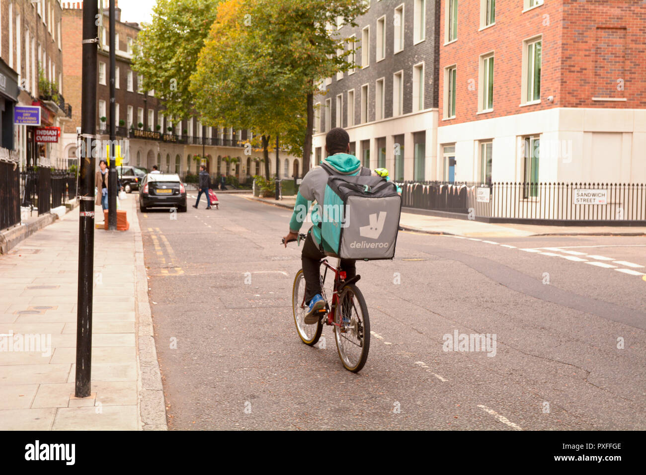 Deliveroo delivery driver on bicyclenear to Sandwich Street  in London, England Stock Photo