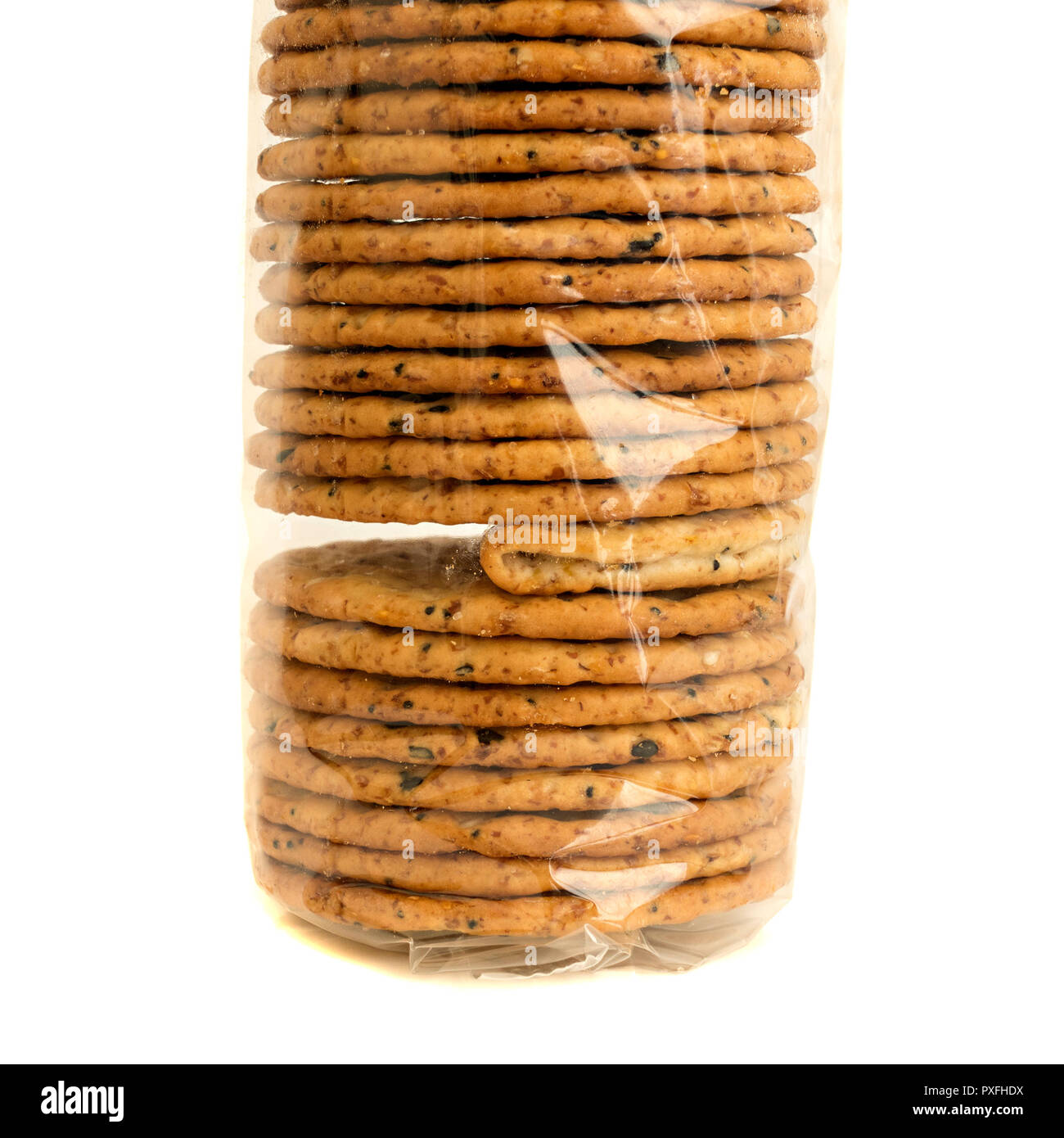 'The Odd One Out' A packet of clear cellophane wrapped biscuits with one faulty folded cracker illustrating a problem or failure in quality control. Stock Photo