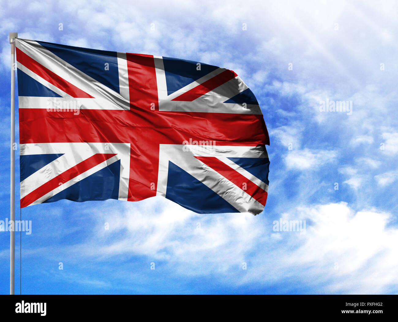 National flag of United Kingdom on a flagpole in front of blue sky. Stock Photo