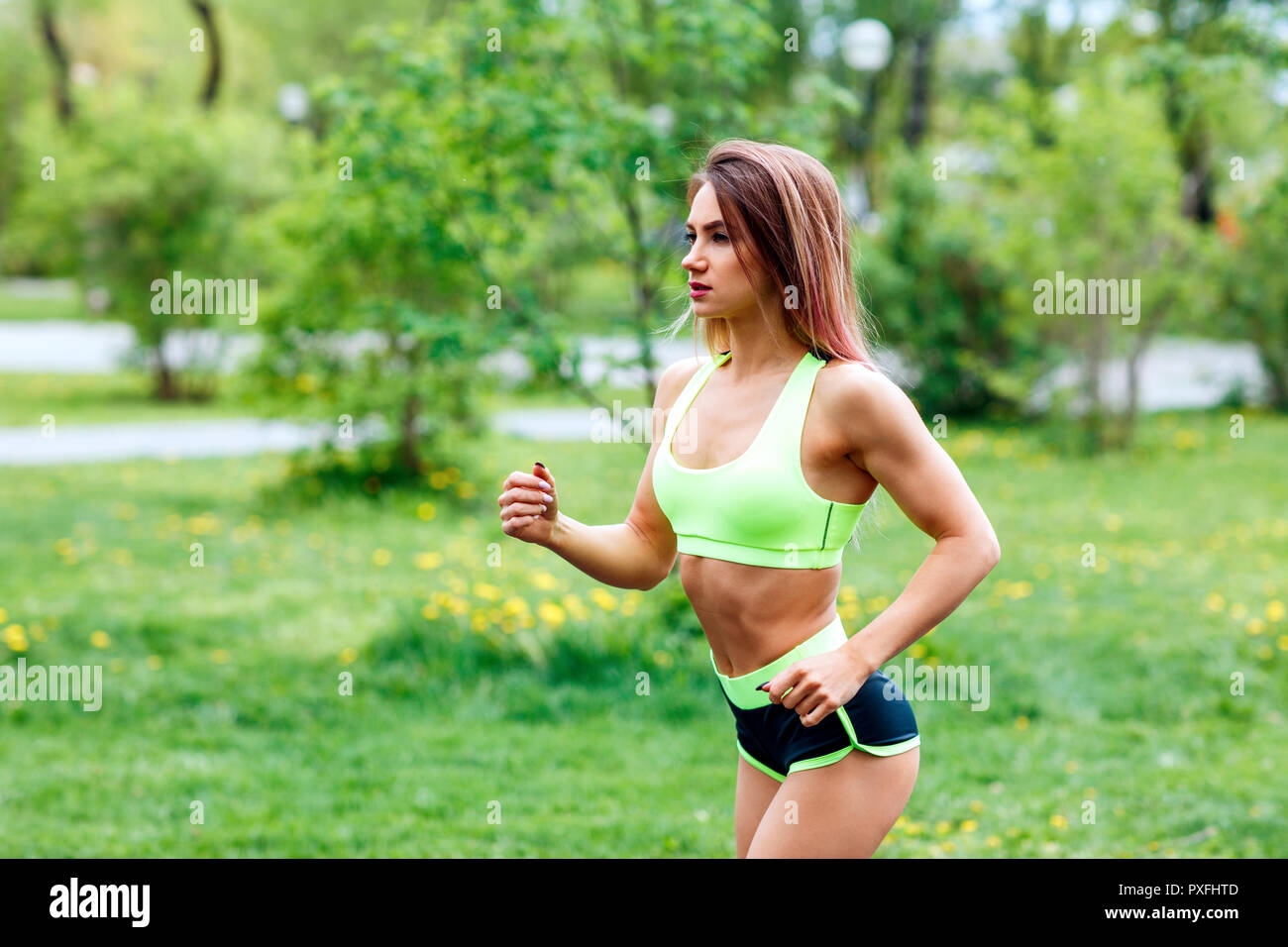 Beautiful young woman running in the green summer park. Stock Photo