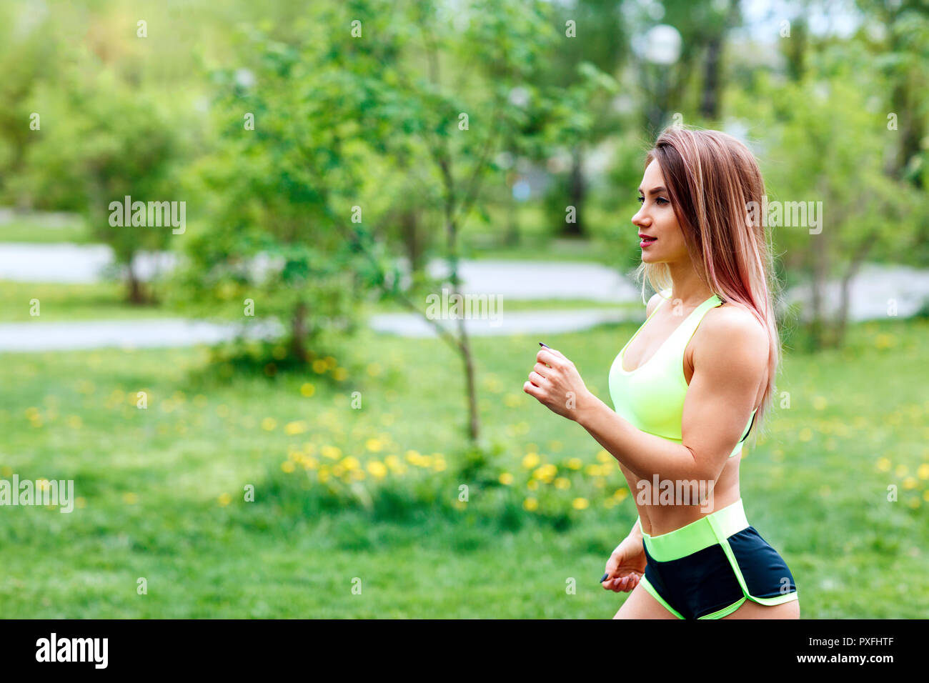 Beautiful young woman running in the green summer park. Stock Photo