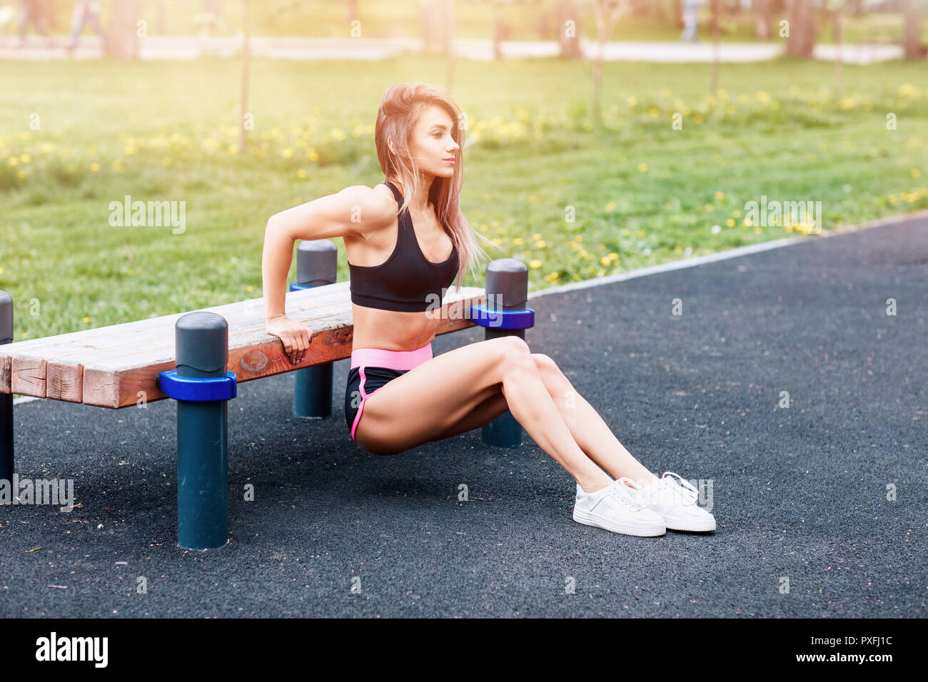 Young Sporty Woman Doing Triceps Dip Exercise On City Street Bench