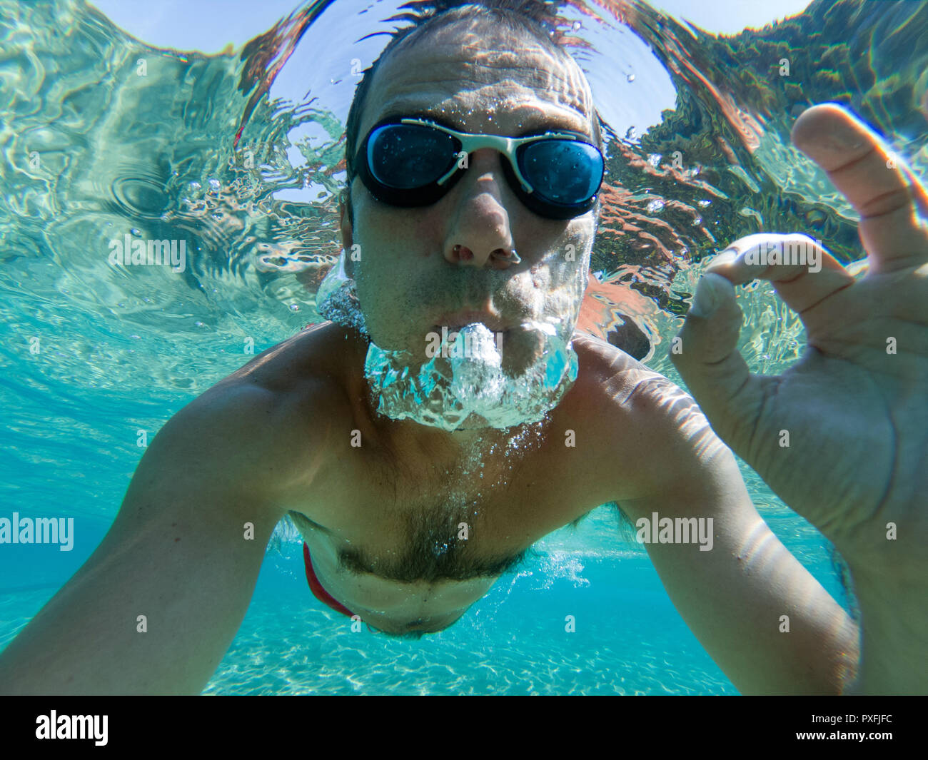 Underwater photo of a man swimming and doing the ok sign tropical sea water Stock Photo