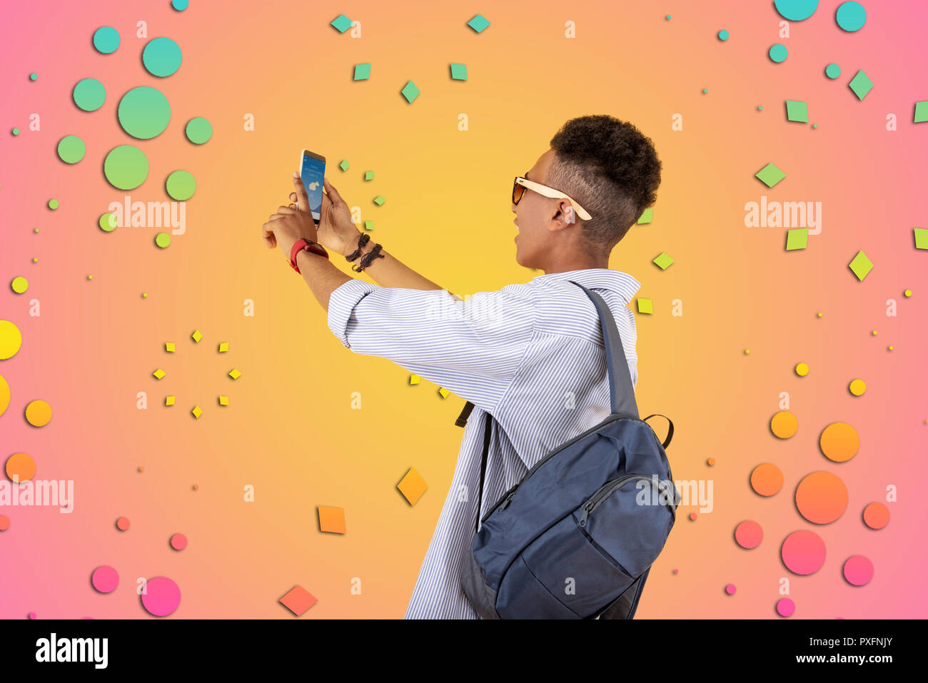 Mulatto teenager wearing blue backpack using his phone checking weather forecast Stock Photo