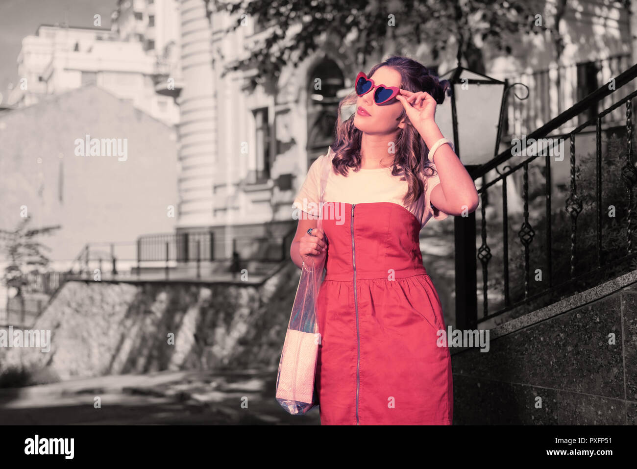 Stylish appealing woman wearing red sunglasses looking at the sky Stock Photo
