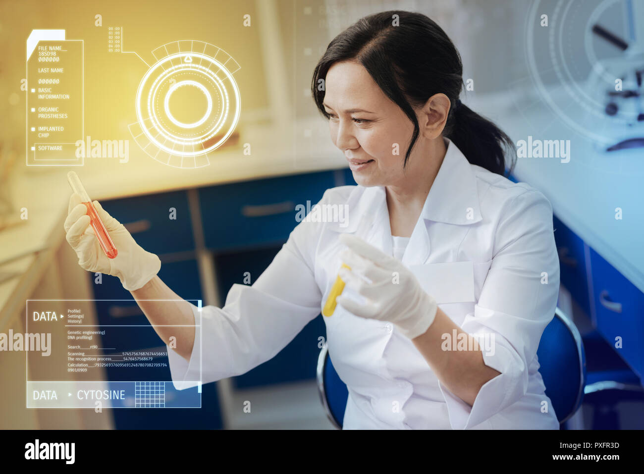 Curious chemist sitting in the lab and holding two test tubes Stock Photo