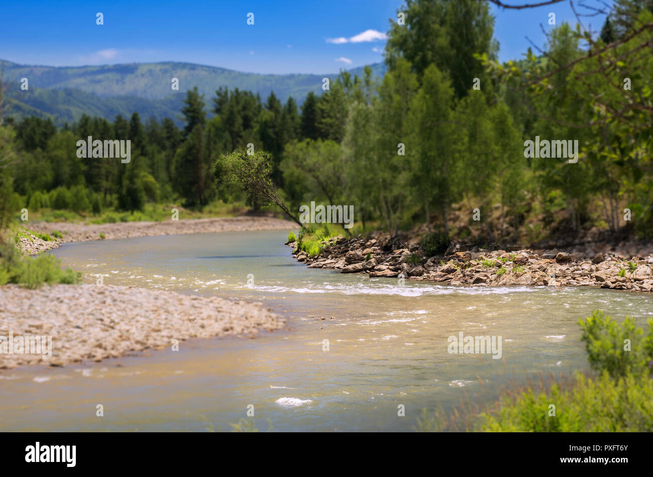 Blue Sky, White Clouds, River Splashing, Flowing Over Rocks. Sunny Summer Day. Ivanovskiy Khrebet Ridge, Altai Mountains, Kazakhstan.  Tilt-Shift Arti Stock Photo