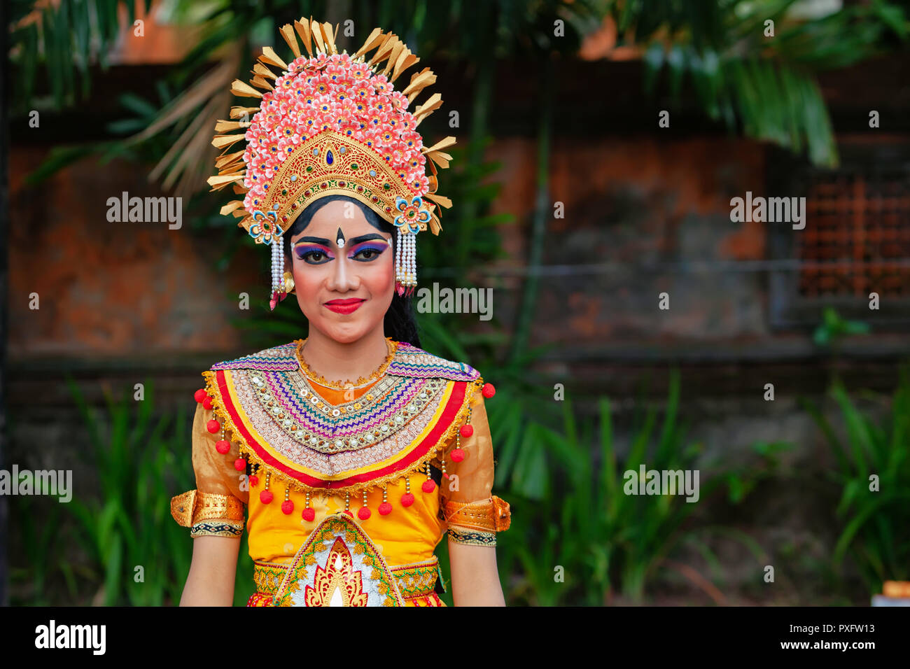 Denpasar, Bali island, Indonesia - June 23, 2018: Face portrait of beautiful young woman in traditional Balinese dance costume with golden headdress Stock Photo