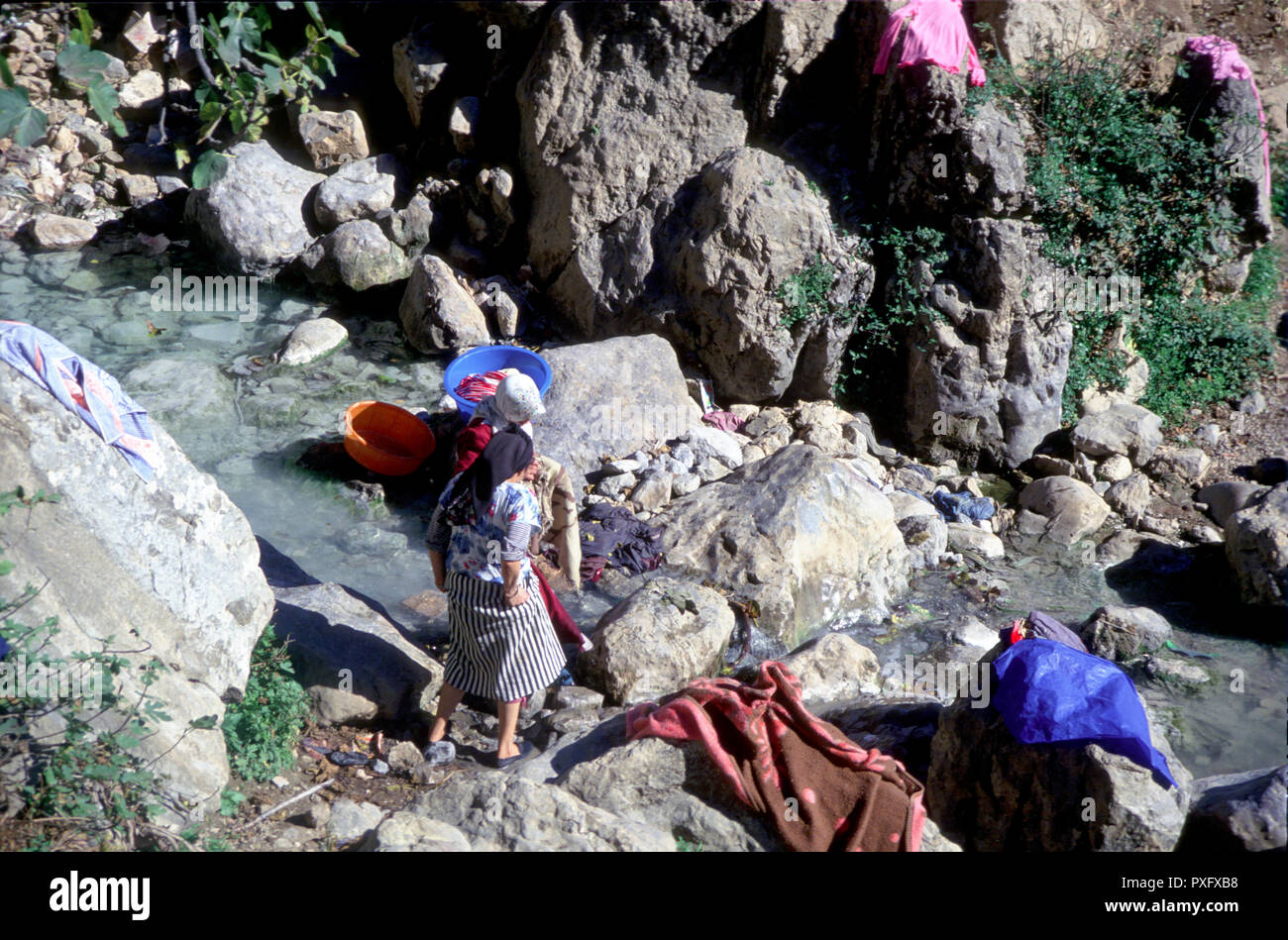 Moroccan women washing clothes on rocks in a stream close to Chefchauen, Rif mountains, Morocco, North Africa Stock Photo