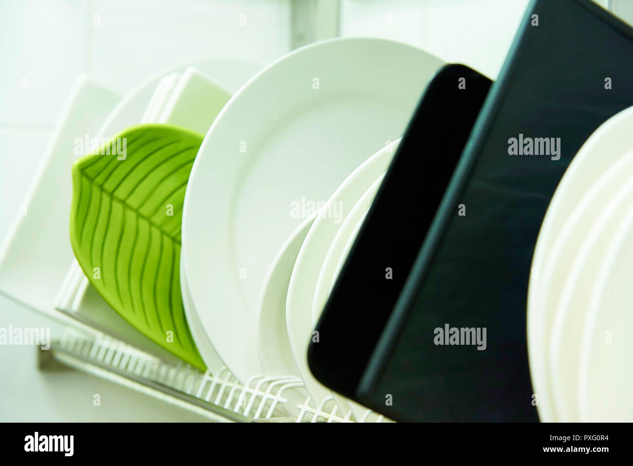 Different clean plates in dish drying rack close-up. Stock Photo