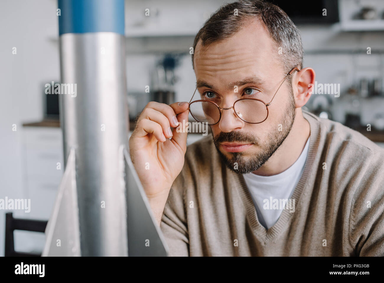 portrait of handsome engineer looking above glasses at rocket model at ...