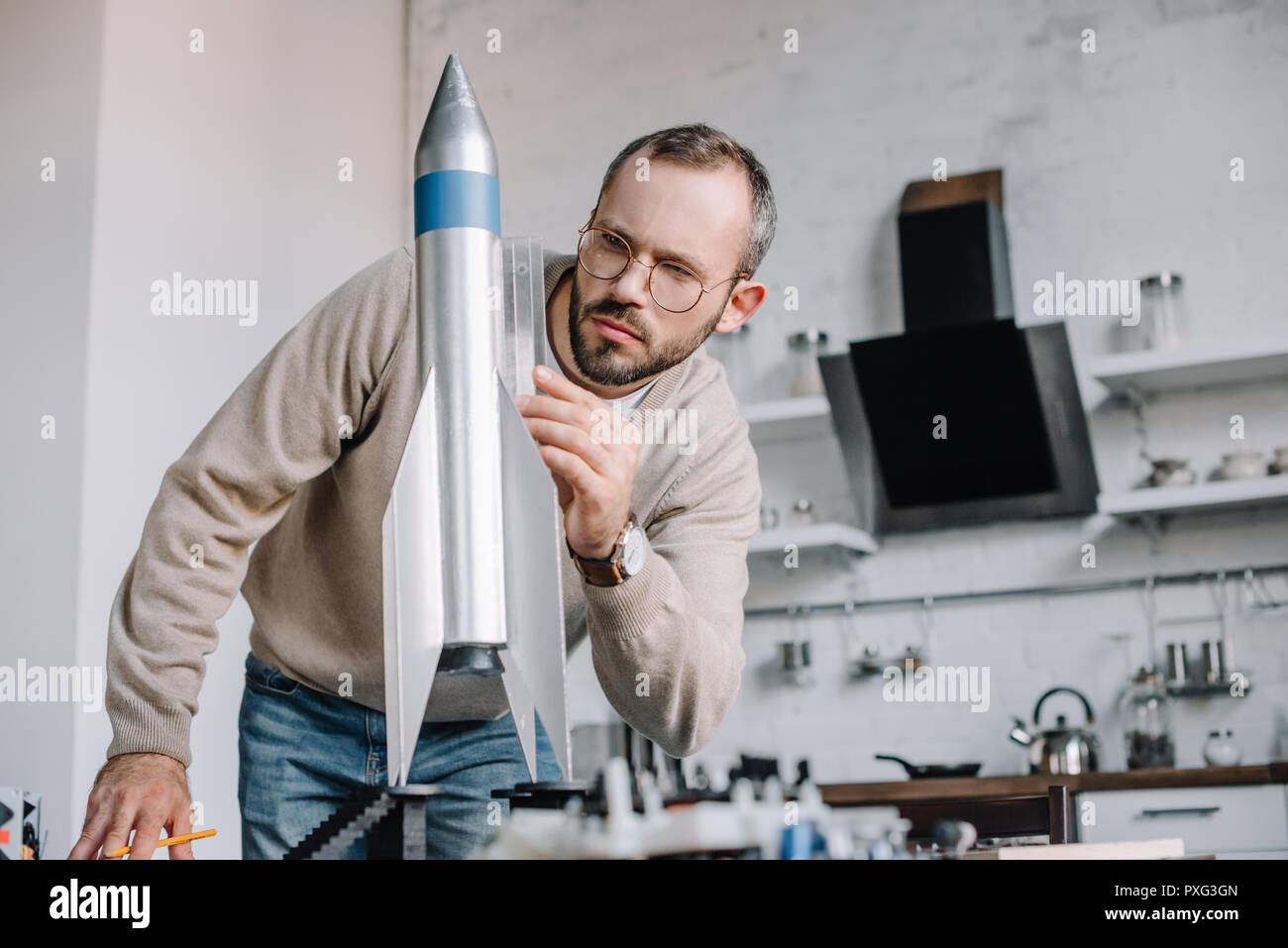 handsome engineer modeling rocket and measuring with ruler at home ...