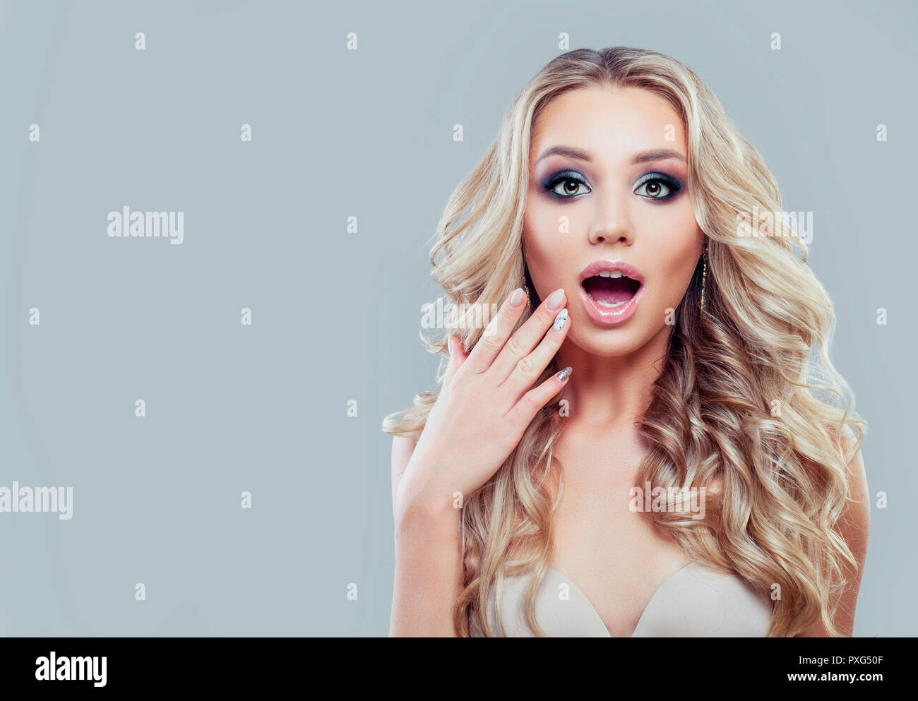 Happy Surprised Woman With Long Curly Hair And Makeup On Blue