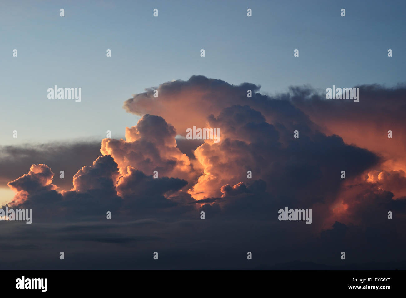 Cumulonimbus cloud formations on tropical sky with horizon is turning yellow at sunset , Nimbus moving , Purple and orange color clouds hunk at night Stock Photo