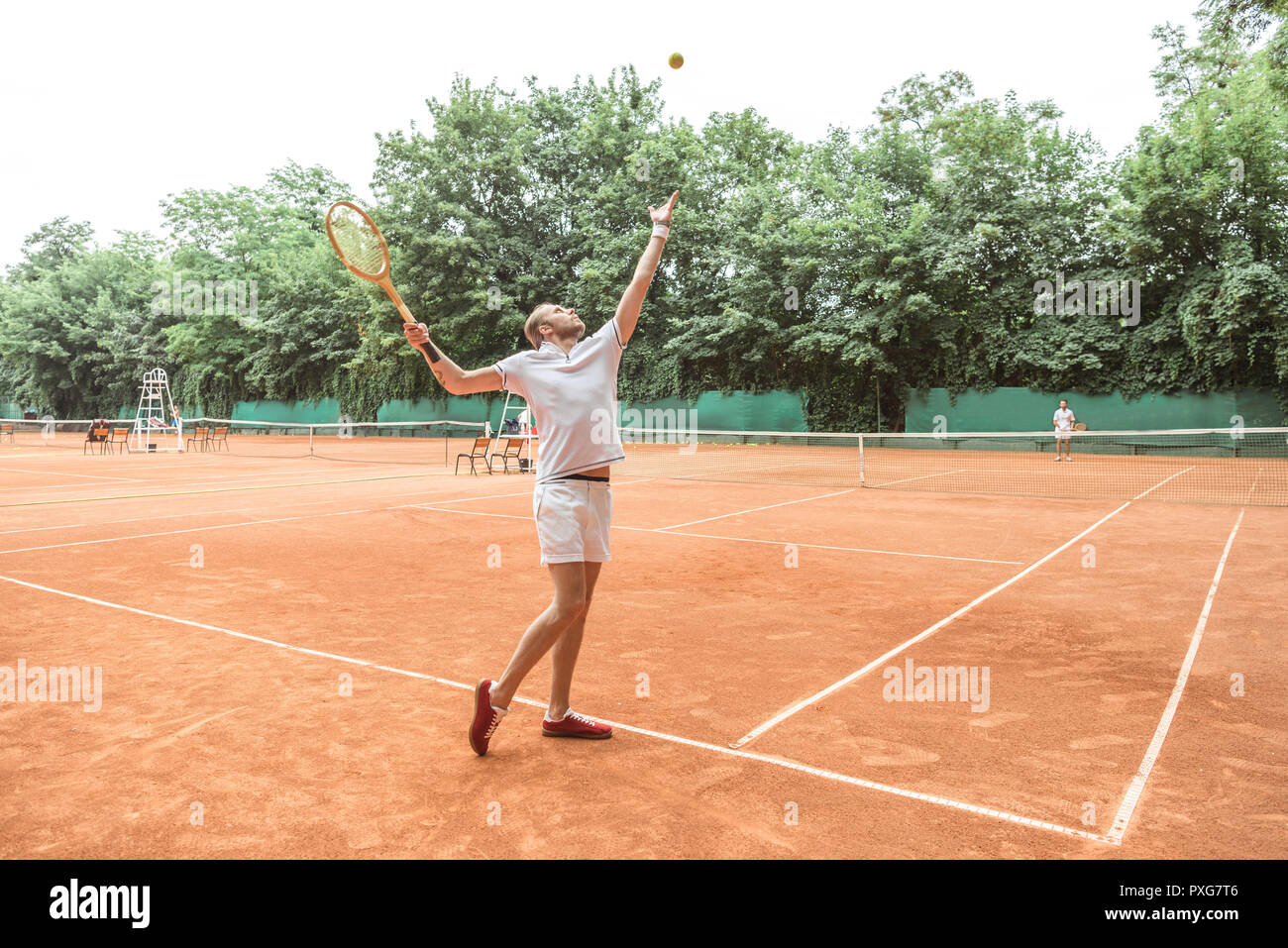 handsome tennis player with racket throwing ball on tennis court Stock