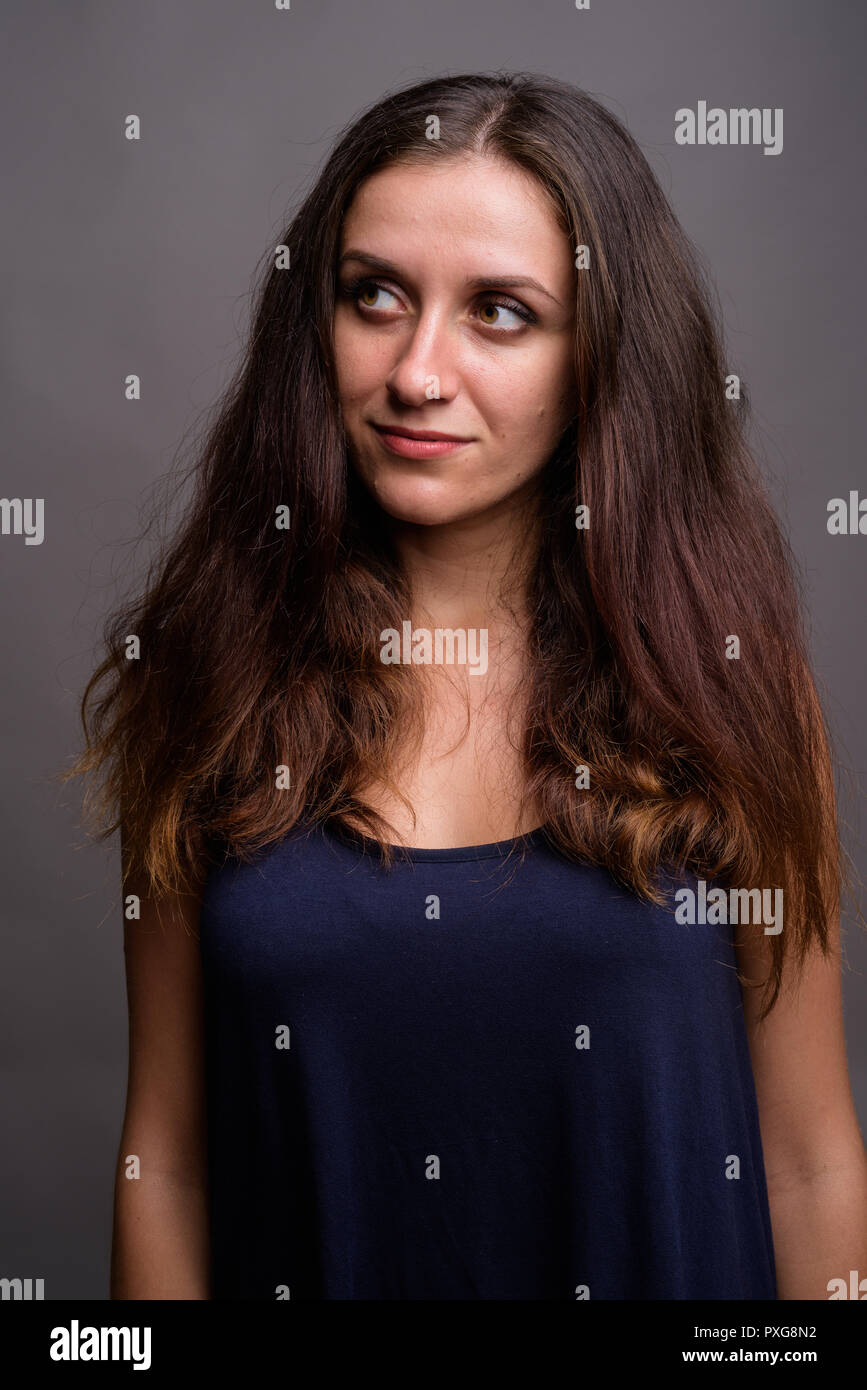 Portrait of young beautiful woman against gray background Stock Photo ...