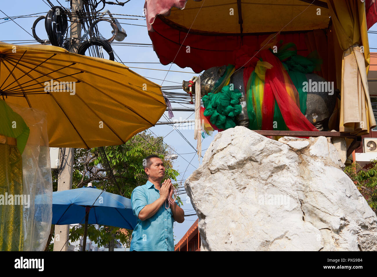 A worshipper at the Sahachat Memorial or 'Pig Shrine', erected for Queen Sri Phatcharinthra, who was born in the Year of the Pig; Bangkok, Thailand Stock Photo