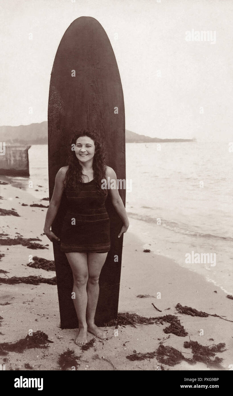 Canadian Rose Heather posing with a wooden surfboard at Gray’s Beach in Waikiki, Honolulu, Hawaii in a photo by Ray Jerome Baker from the 1910s. Stock Photo