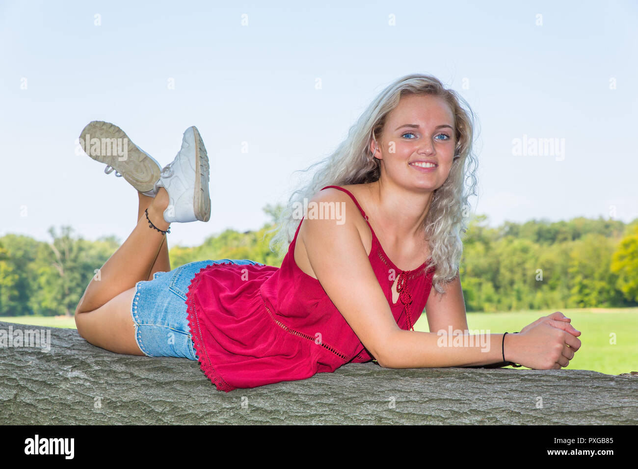 Young caucasian woman lying on tree trunk in nature Stock Photo