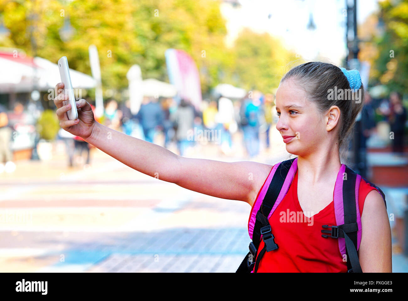 Tourist child girl with backpack taking selfies on smartphone Stock Photo