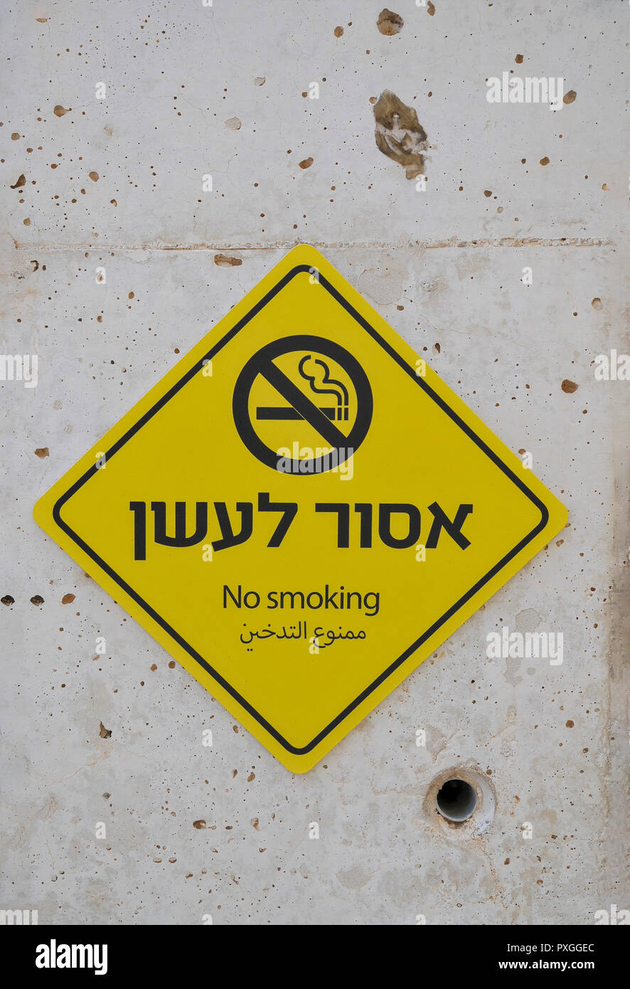 Yellow, NO SMOKING sign in Hebrew and Arabic on a concrete wall Stock Photo