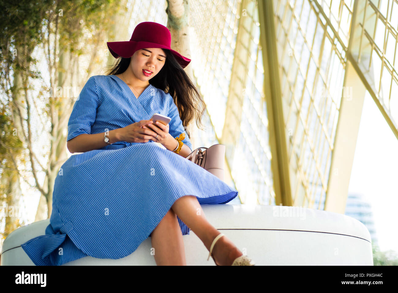 Fashionable Asian girl using phone on a balcony outdoors Stock Photo