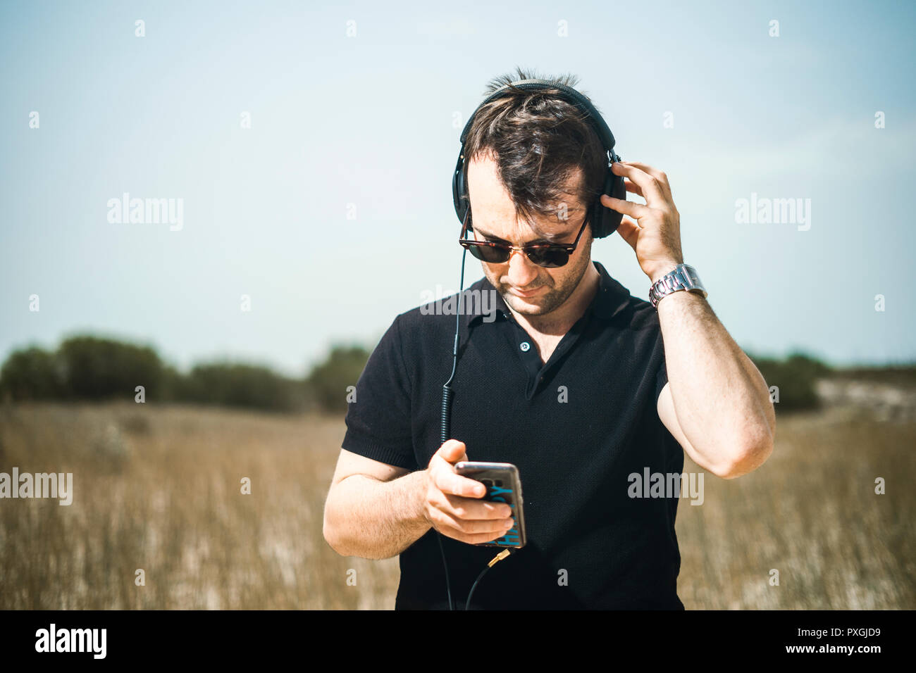 Handsome young man playing music from his smartphone on his headphones Stock Photo