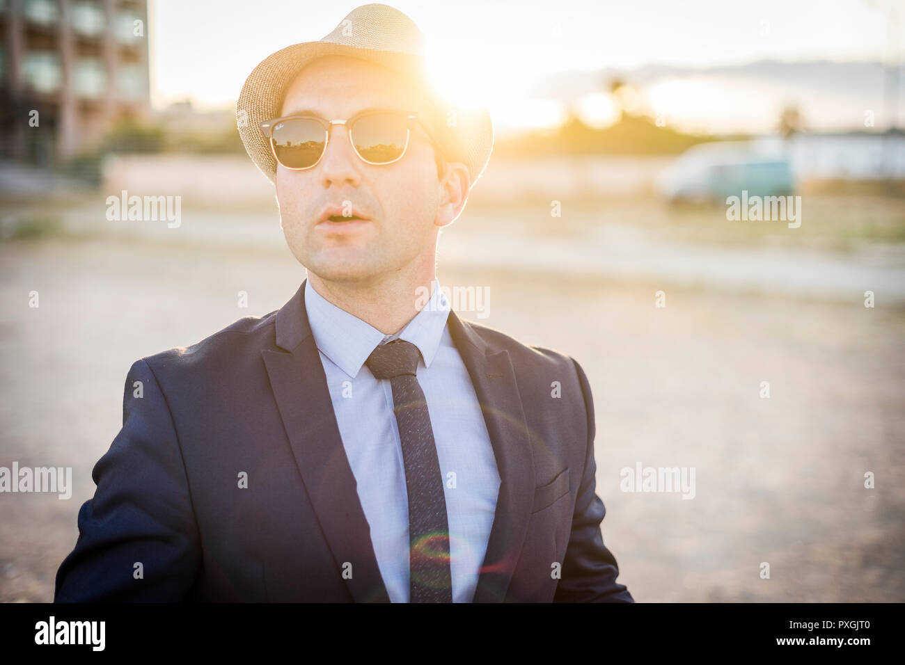 Lifestyle portrait of vintage looking young man in suit with sunglasses at sunset Stock Photo