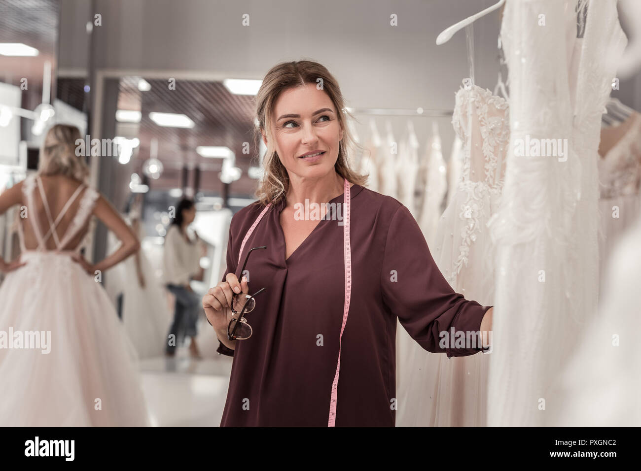 Pleasant female designer looking at the wedding dress Stock Photo