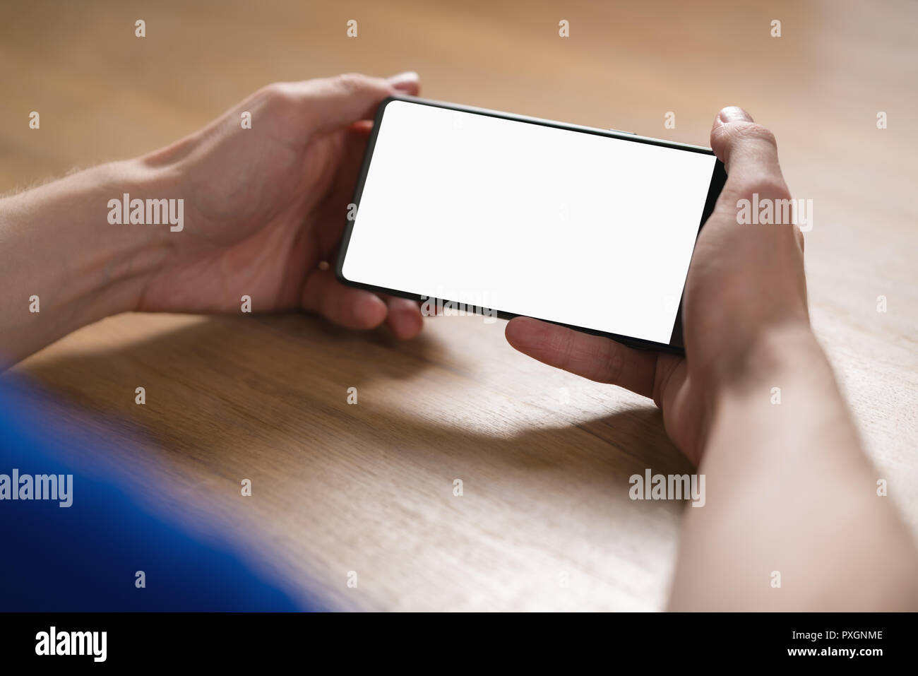 young man hands holding smartphone with blank white screen in landscape mode Stock Photo