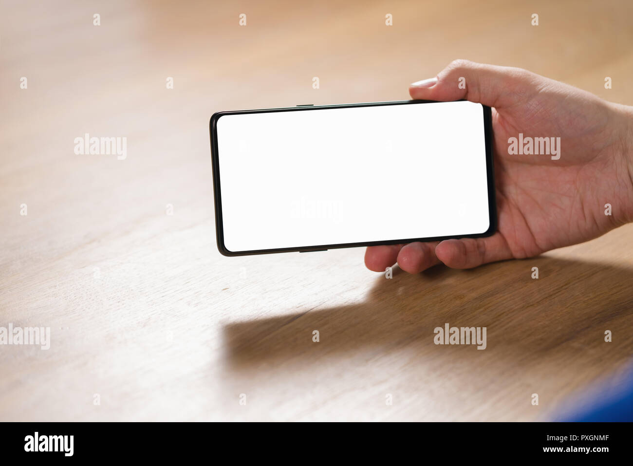 young man hand holding smartphone with blank white screen in landscape mode Stock Photo