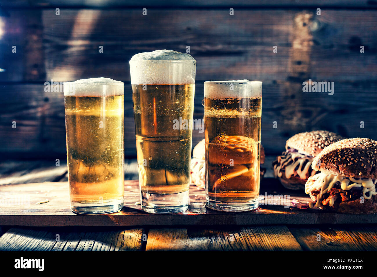 Street food. A two big burgers with glasses of light beer. On a wooden background. close up. rustic style Stock Photo