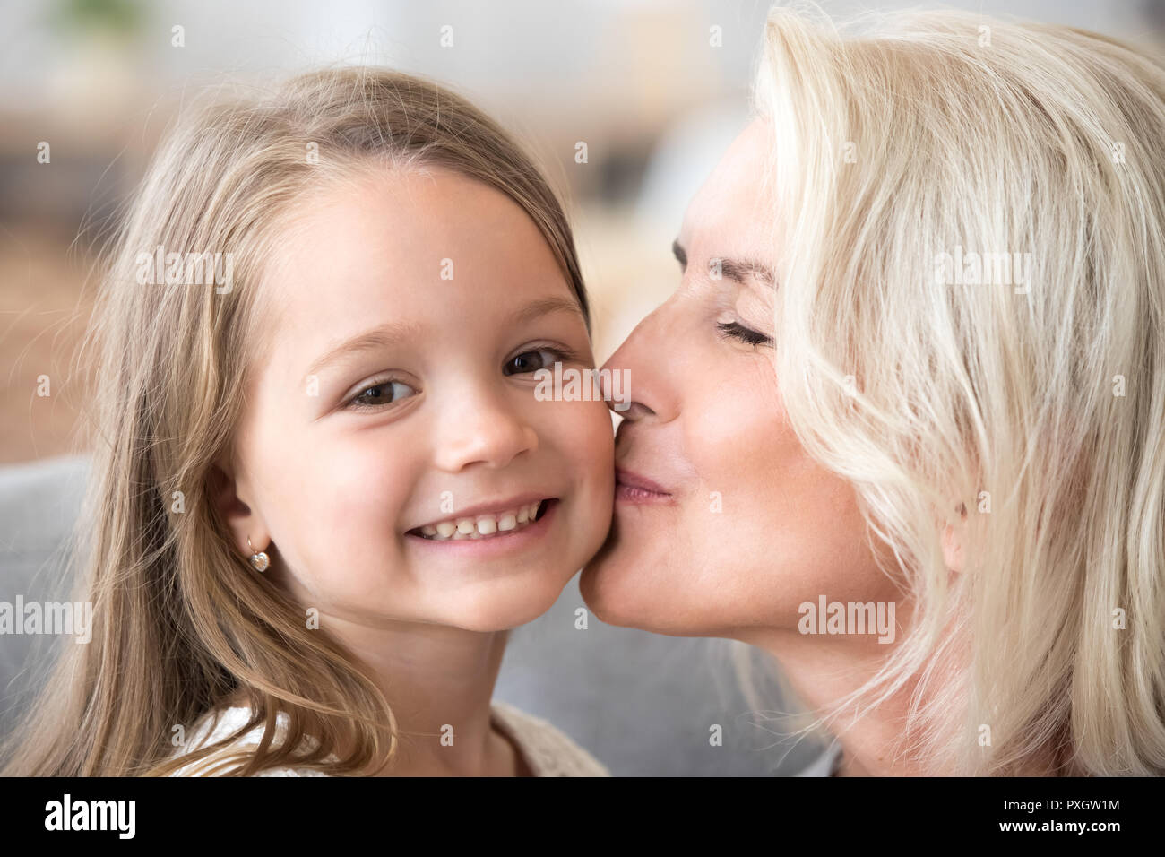 Portrait of loving grandmother kissing granddaughter on cheek Stock Photo