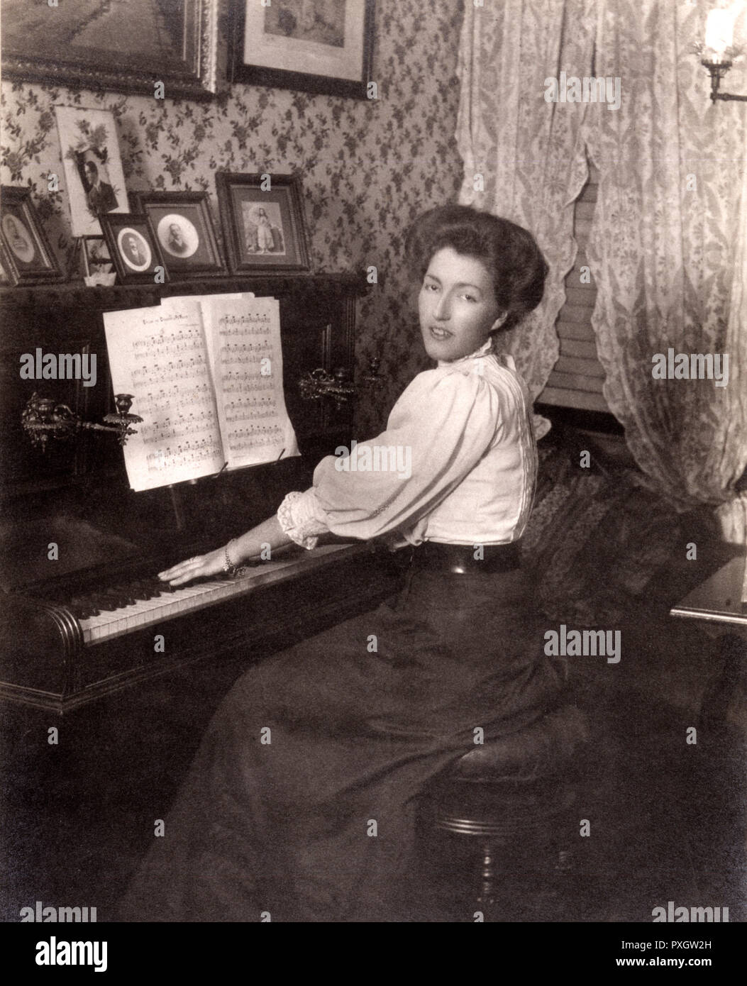 Lady playing an upright piano in her front room Stock Photo
