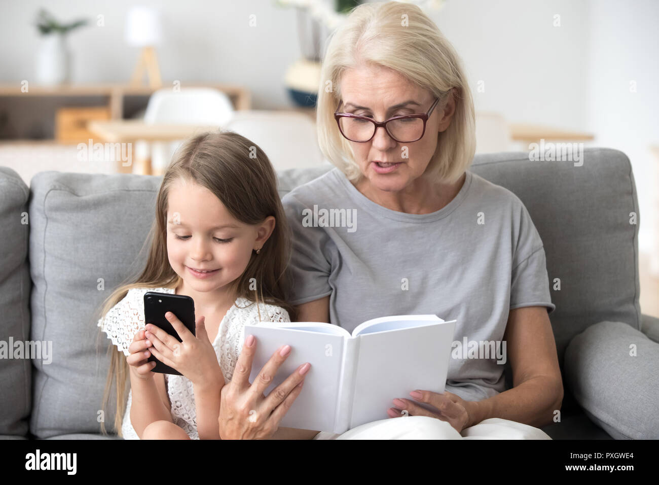 Grandmother read book to addicted to smartphone little kid Stock Photo