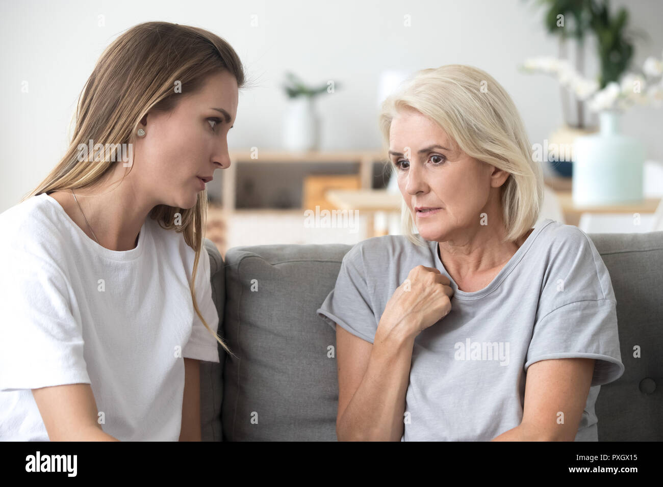 Concerned aged mom and adult daughter talk at home Stock Photo