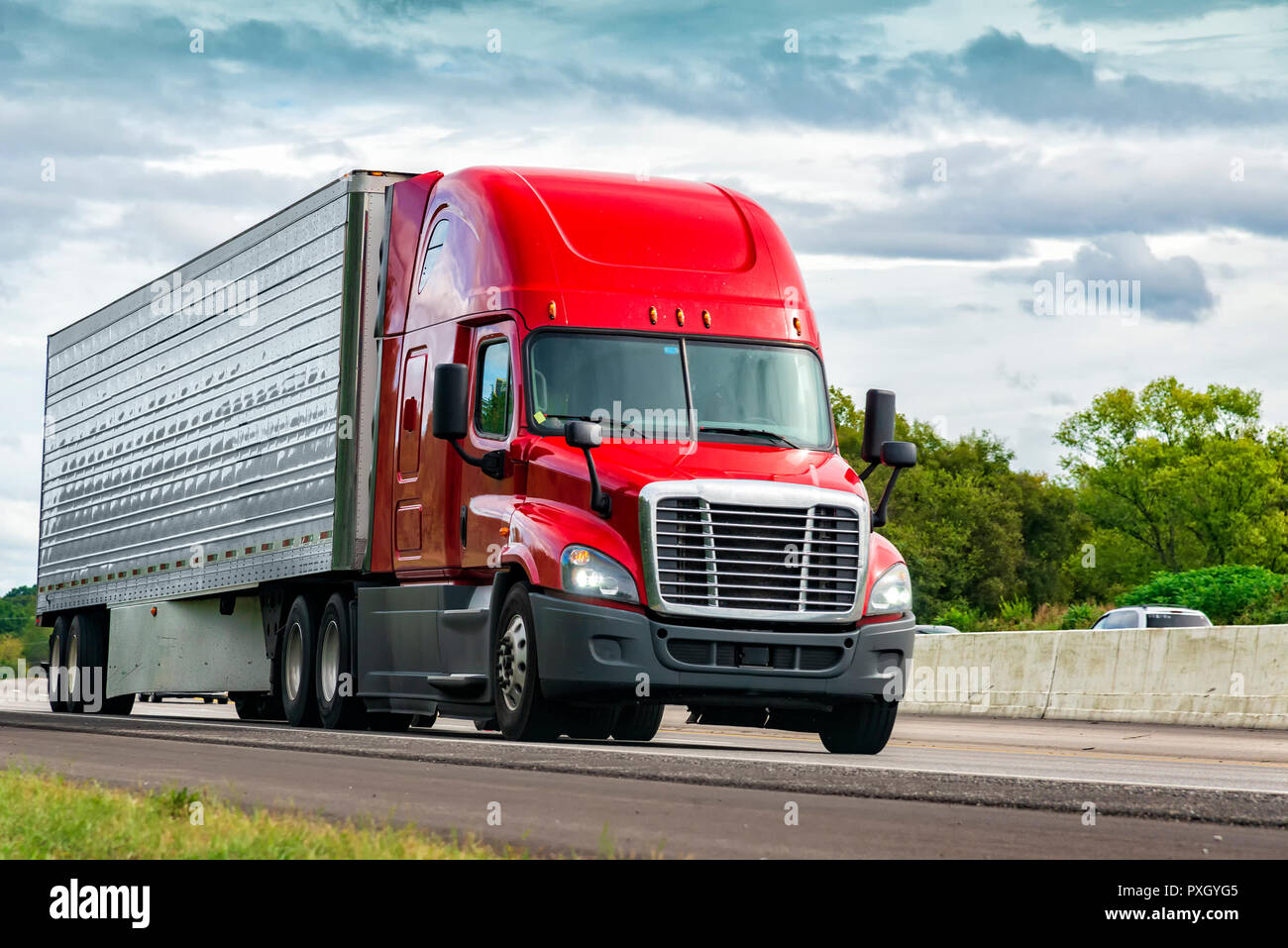 Horizontal shot of a red semi-truck on an interstate highway. Stock Photo