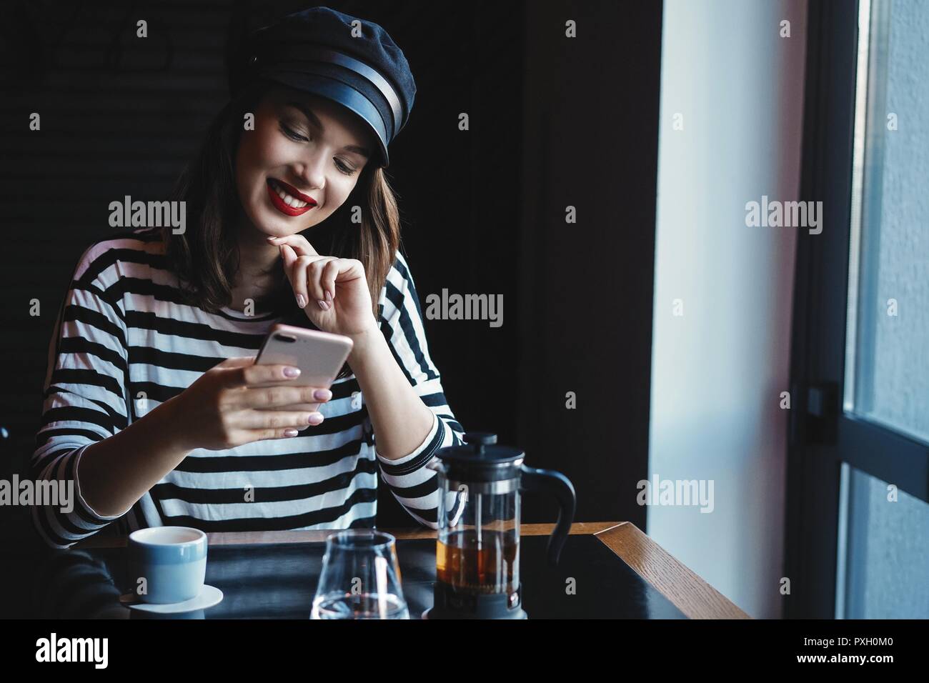 Portrait of young beautiful woman using her mobile phone in cafe. Stock Photo