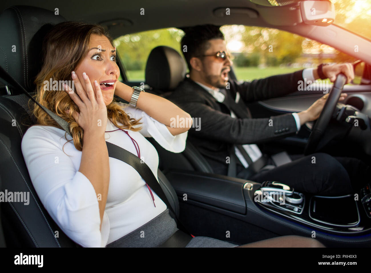 Angry business man with sunglasses driving and honking  while woman is afraid Stock Photo