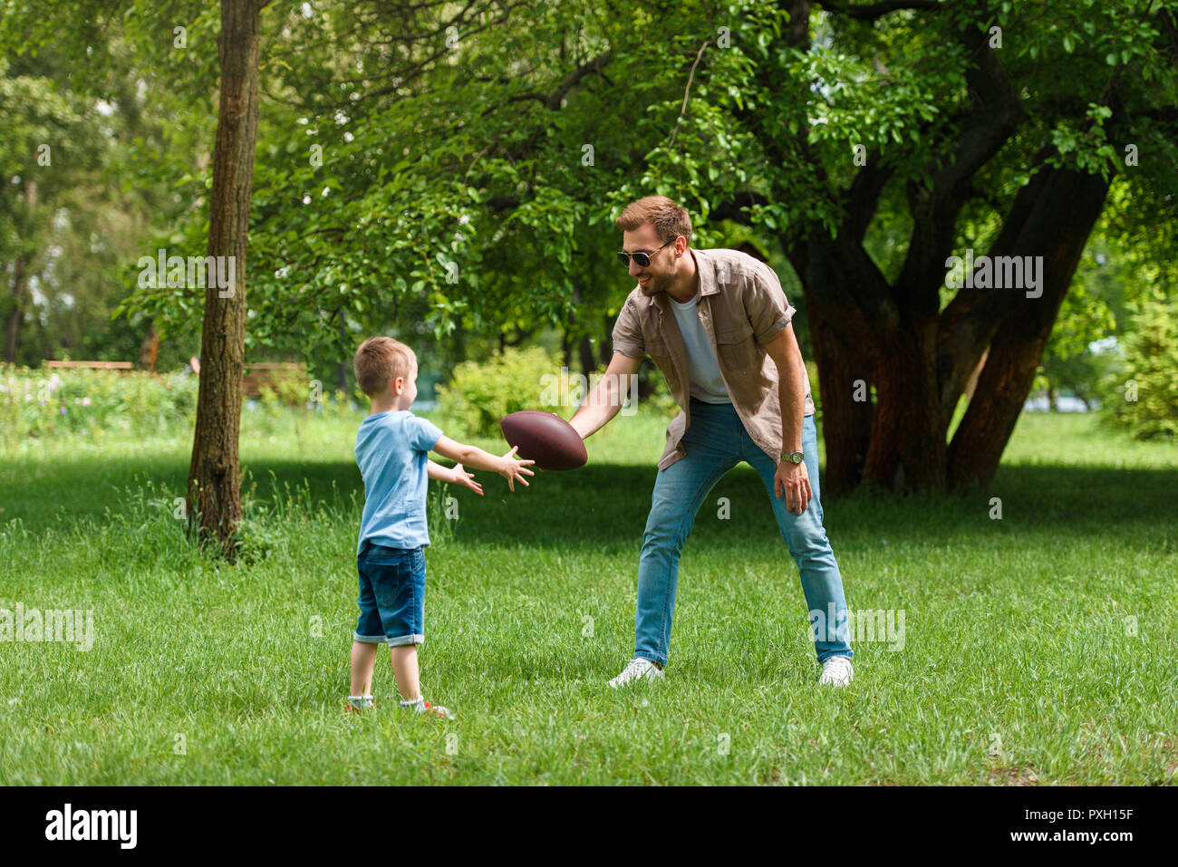 happy father and son playing american football at park Stock Photo - Alamy