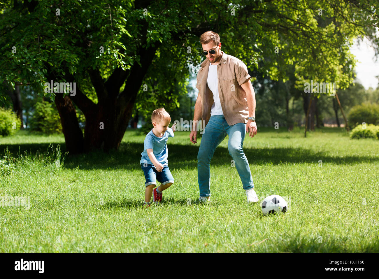 father and son playing football on grass at park Stock Photo - Alamy